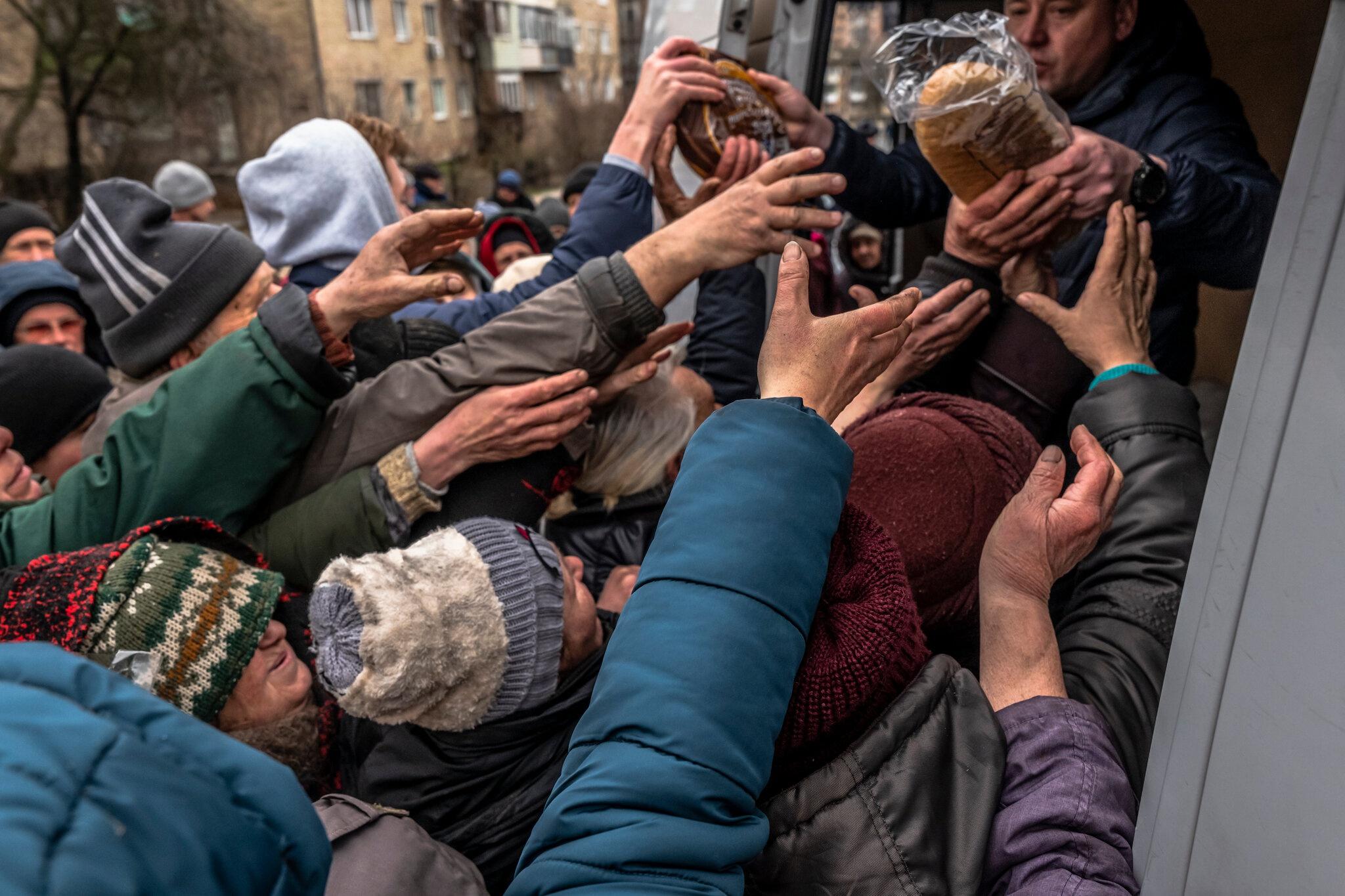Người dân xúm lại nhận thực phẩm từ binh sĩ Ukraine vào hôm 2/4. Ảnh: New York Times.