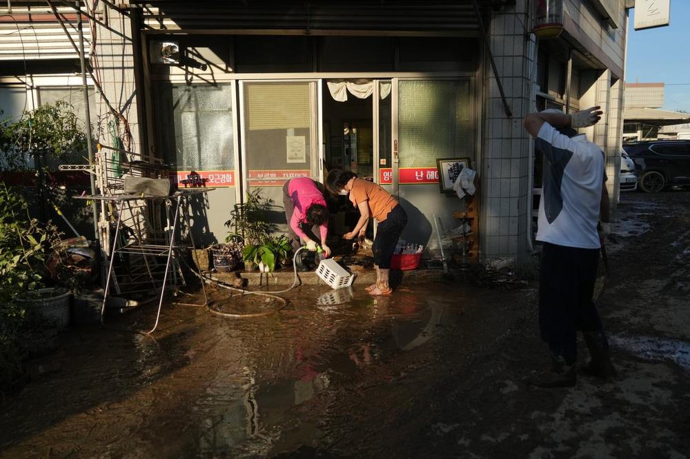 Một số người dân ở Thành phố Gyeongju đang cố gắng trục vớt đồ đạc bị chìm trong nước lũ.