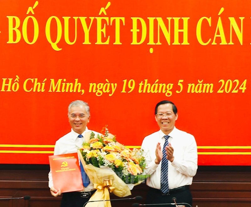 Chủ tịch UBND TPHCM Phan Văn Mãi (phải) tặng hoa chúc mừng ông Ngô Minh Châu. (Ảnh: Trang tin Thành ủy TPHCM)