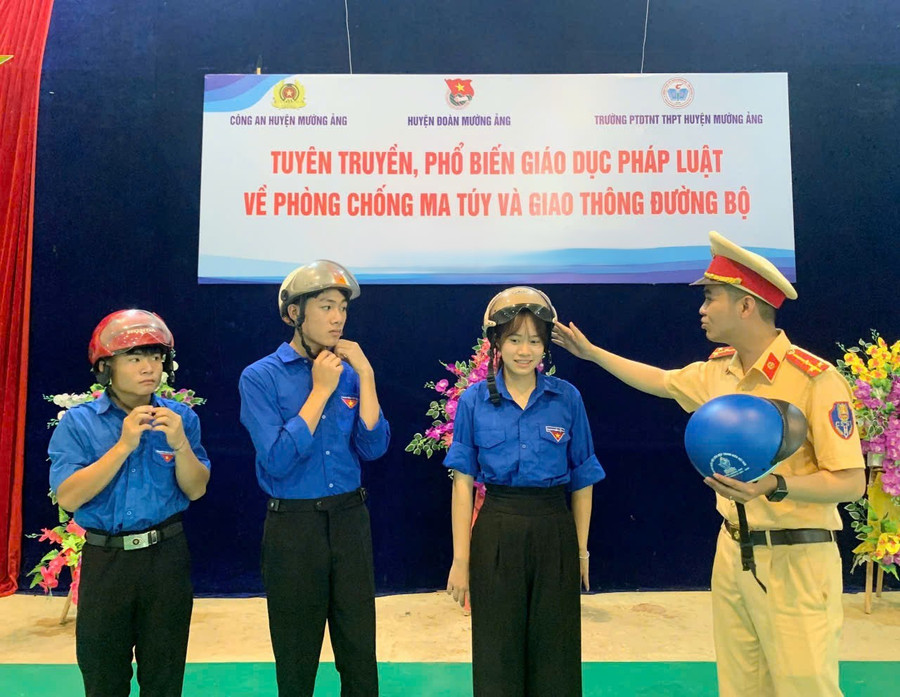 Cán bộ Đội cảnh sát giao thông hướng dẫn các em học sinh đội mũ bảo hiểm đúng cách.