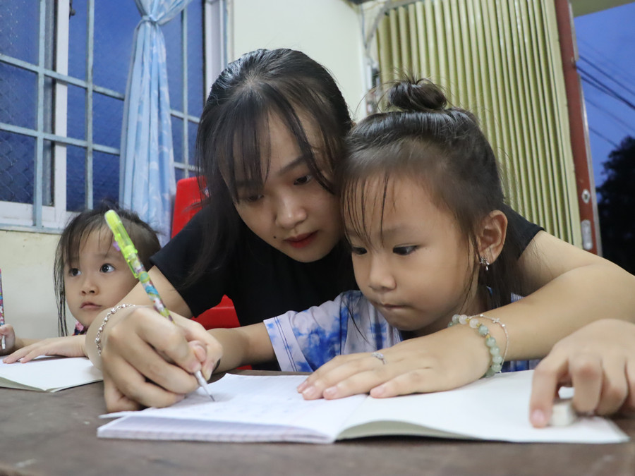 Sinh viên Bùi Thị Hương Giang hỗ trợ học sinh viết chữ. lop-hoc-dac-biet-giua-long-thanh-pho-5-7594.jpg