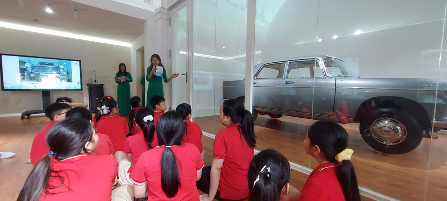 Học sinh Trường Tiểu học Nghĩa Dũng được trải nghiệm với hoạt động “Nghe hiện vật kể chuyện” qua việc xem video và trực tiếp ngắm nhìn xe Peugeot 404. Ảnh: Bình Thanh. giao-duc-di-san-tu-hien-vat-ke-chuyen-3.jpg