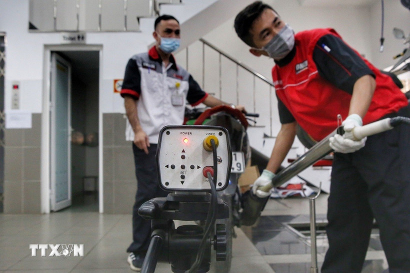 Các nhân viên kiểm tra khí thải xe máy. (Ảnh: Tuấn Đức/TTXVN).