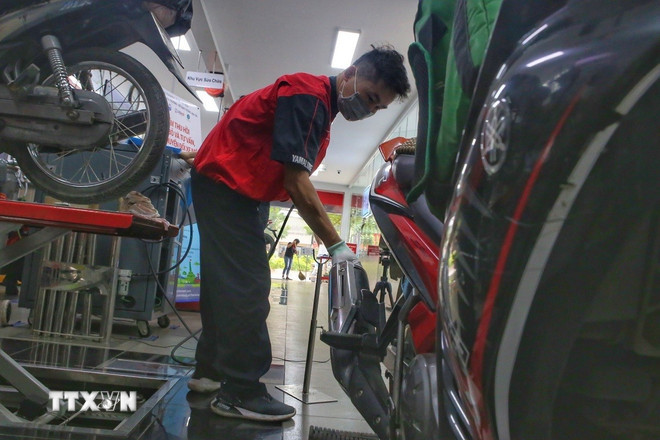 Các nhân viên kiểm tra khí thải xe máy. (Ảnh: Tuấn Đức/TTXVN).