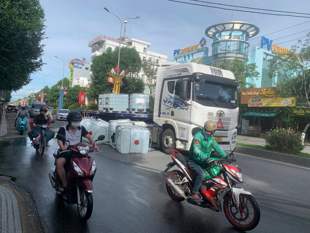 Xe tải chở làm rơi nhiều thùng chất lỏng đổ tràn ra đường nghi hóa chất - ảnh 1