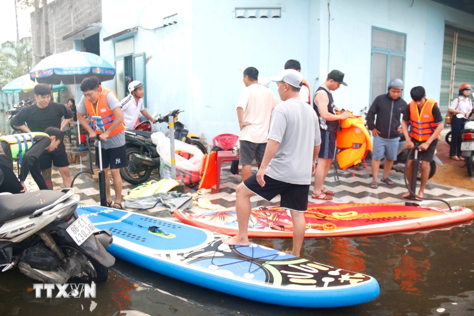 Thanh niên địa phương bơm xuồng phao đến hỗ trợ người dân di chuyển ra khỏi vùng ngập sâu. (Ảnh: Nguyễn Thanh/TTXVN)