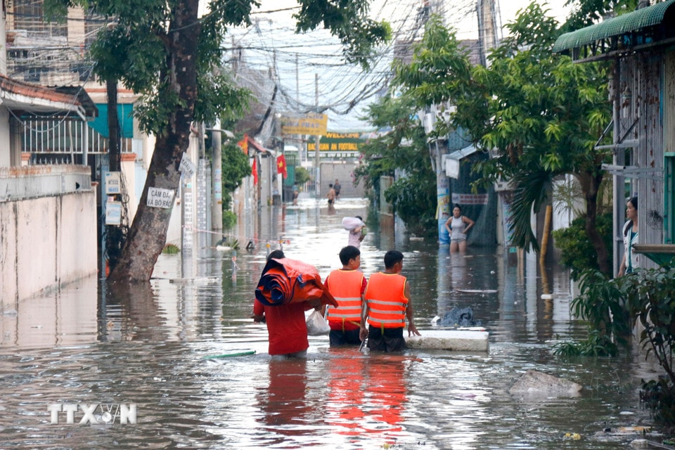 Lực lượng chức năng hỗ trợ người dân di chuyển đồ đạc tại khu vực ngập sâu đến nơi ở khác. (Ảnh: Nguyễn Thanh/TTXVN)