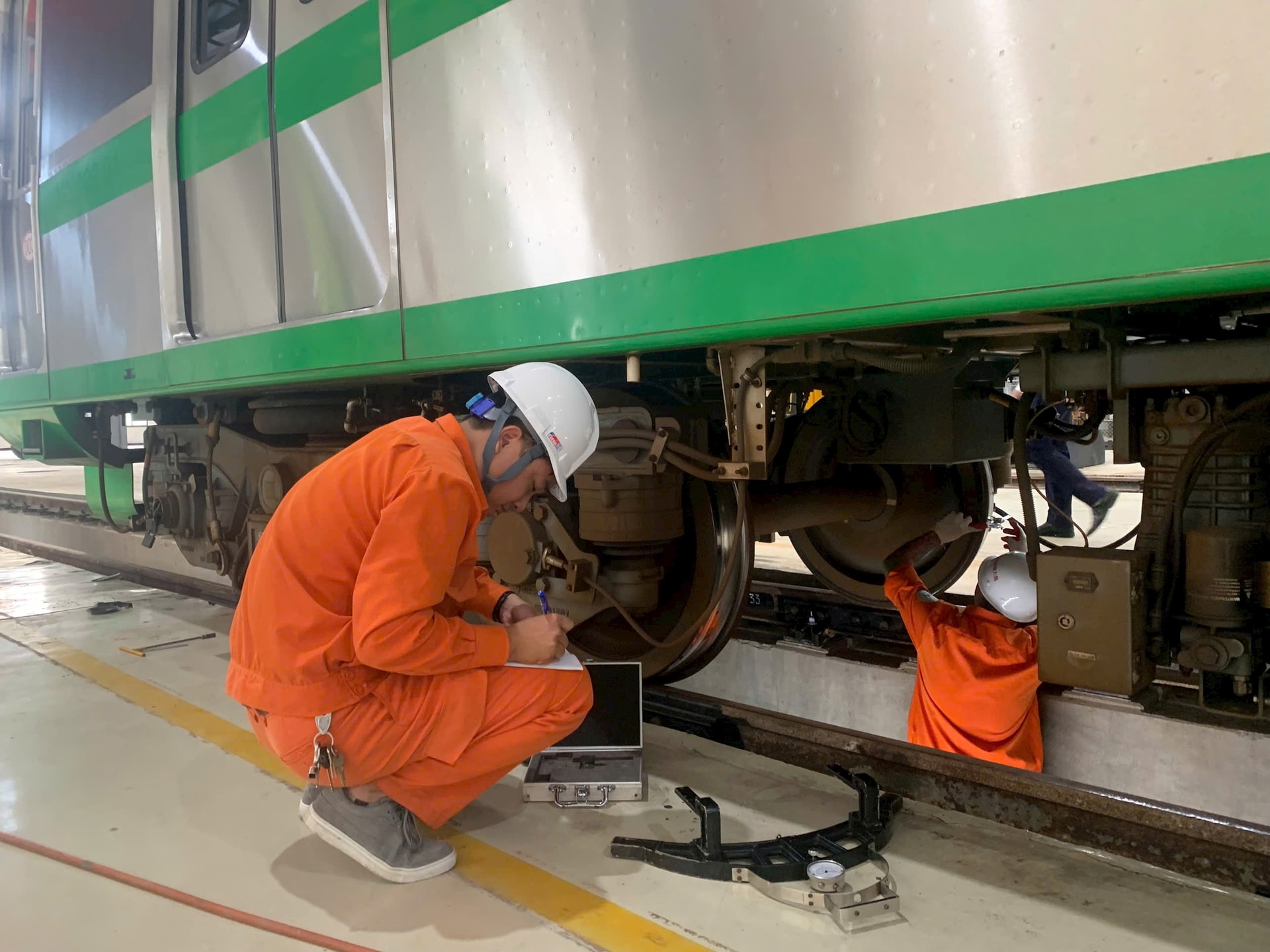 Các nhân viên tỉ mẩn đo và ghi chép độ mòn của từng bánh tàu. Ảnh: Tuấn Lương.