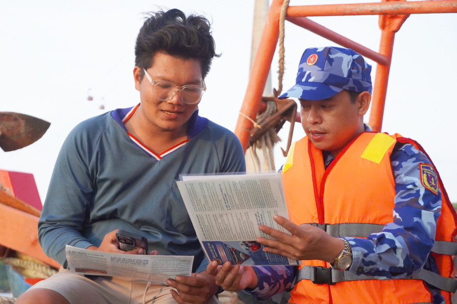 Thiếu tá Hoàng Mạnh Hùng (bên phải) hướng dẫn ngư dân Phan Tuấn Anh quét mã QR. Ảnh: Yến Phương canh-sat-bien-3.jpg